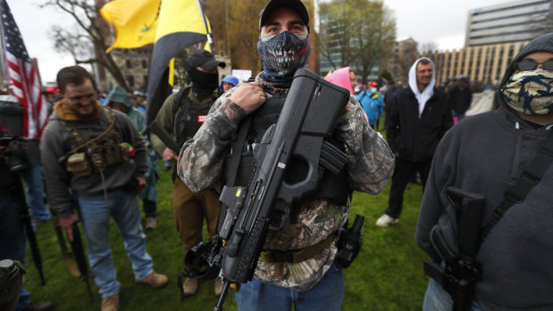 A protester shows off his powerful gun as demonstrators swarmed the State Capitol in Lansing, Michigan.