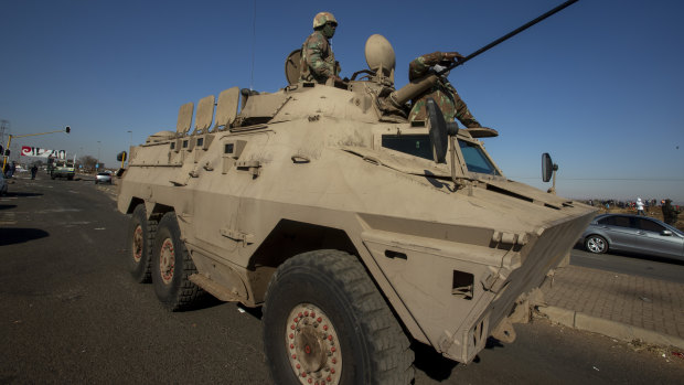 Soldiers on a military vehicle watch the crowd, as community leaders speaks to a group in an effort to stop them from entering a shopping mall in Vosloorus, east of in Johannesburg, South Africa.