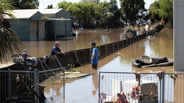 Two neighbours catch up as they survey wreckage around their homes.