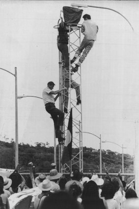 Police pursue two protesters up a security tower.