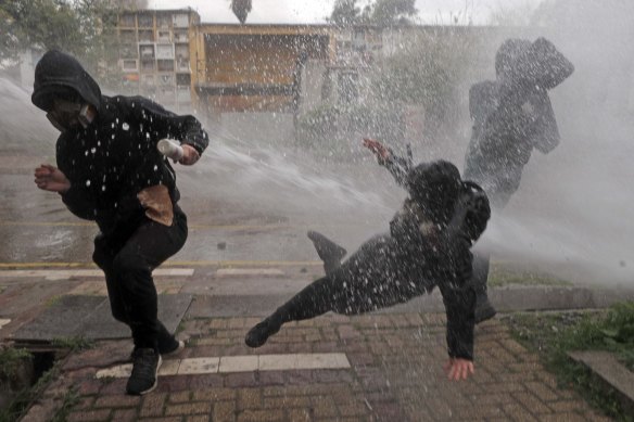Protesters are hit by a police water cannon during clashes at a march marking the 50th anniversary of the military coup led by General Augusto Pinochet, in Santiago, Chile.