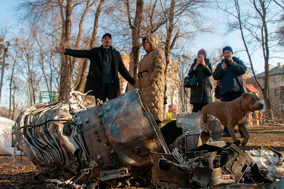 People stand next to fragments of military equipment on the street in the aftermath of an apparent Russian strike in Kharkiv, Ukraine on Thursday.