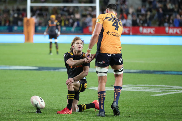 Damian McKenzie shakes the hand of Darcy Swain after the Brumbies lock was yellow carded.