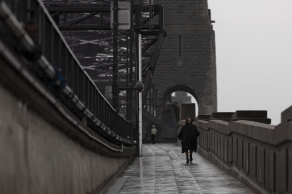 A man walks across the Sydney Harbour Bridge under heavy rain yesterday.