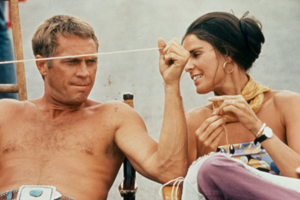 A shirtless Steve McQueen sitting next to Ali MacGraw on the set of the film 'The Getaway', 1972.
