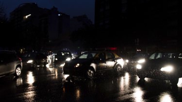 Cars drive through an unlit street during a blackout in Buenos Aires.