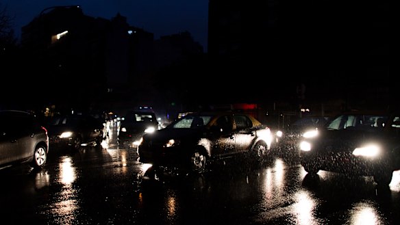 Cars drive through an unlit street during a blackout in Buenos Aires.