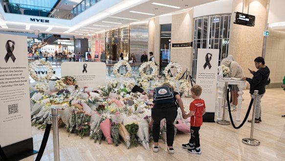 A mother and young son leave flowers at a memorial to the victims of last week’s Westfield Bondi Junction tragedy.