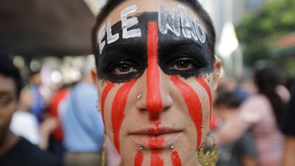 A woman poses for a photo with the words "Not him" written in Portuguese on her face during a protest against Jair Bolsonaro, a far-right presidential candidate in Sao Paulo.