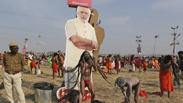A policeman stands next to a cut out photograph of Indian Prime Minister Narendra Modi as Hindu holy men participate in a ritual after a holy dip at Sangam, the confluence of sacred rivers the Yamuna, the Ganges and the mythical Saraswat in India.