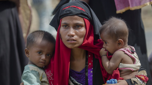 In this 2017 photo, a Rohingya Muslim woman, Rukaya Begum, who crossed over from Myanmar into Bangladesh, holds her son Mahbubur Rehman, left and her daughter Rehana Bibi, after the government moved them to newly allocated refugee camp areas, near Kutupalong, Bangladesh.