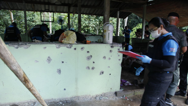 Bullet marks are seen on a wall as police inspect the shooting scene after 15 personnel were killed at a security checkpoint in Yala province, Thailand.