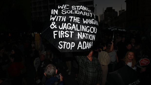 Protesters opposing to the construction of the Adani coal mine hold signs during a rally in Brisbane on Friday.