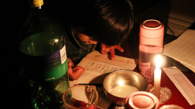 Xu Yuanyuan, then 7, does her maths homework by candlelight in Picun Village, Beijing.