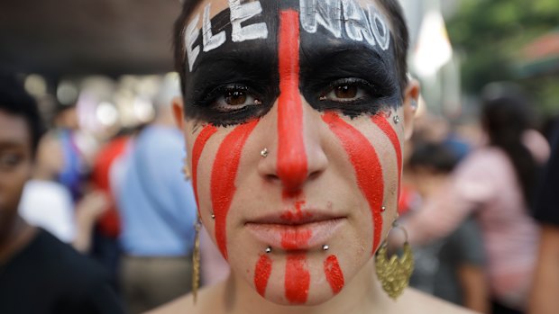 A woman poses for a photo with the words "Not him" written in Portuguese on her face during a protest against Jair Bolsonaro, a far-right presidential candidate in Sao Paulo.