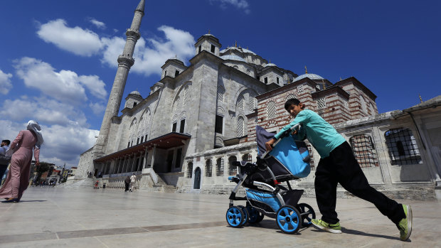 A Syrian boy pushes a pram past Fatih mosque in Istanbul. Syrians say Turkey has been detaining and forcing some refugees to return home in the past month. 