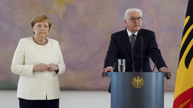 German Chancellor Angela Merkel, left, steadies her hands on Thursday.