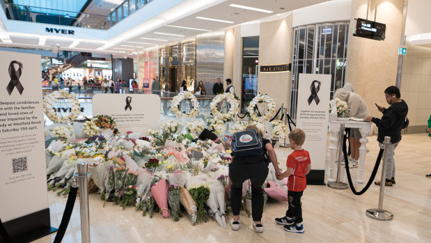 A mother and young son leave flowers at a memorial to the victims of last week’s Westfield Bondi Junction tragedy.