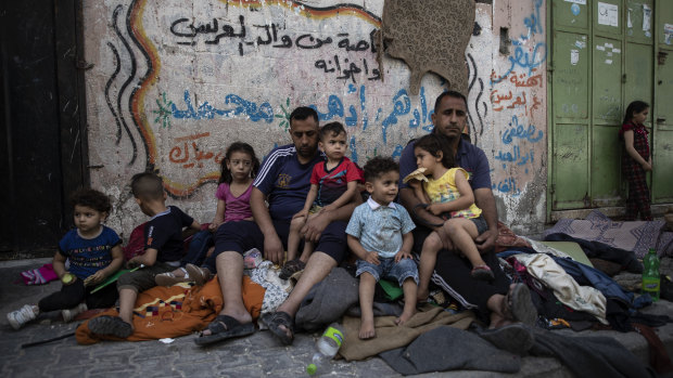 A Palestinian family sits outside their home in Gaza after it was hit by an Israeli air strike.