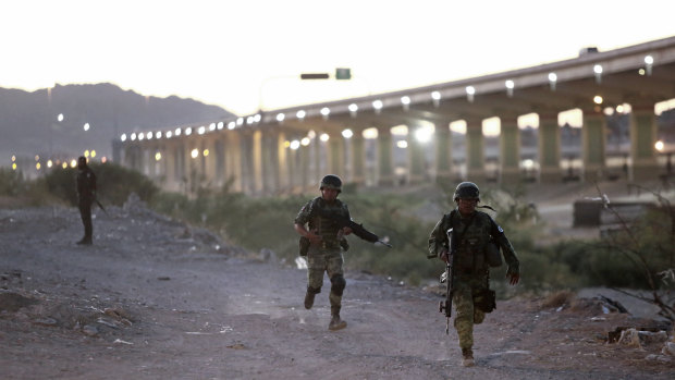 Military police wearing the insignia of the new National Guard run to detain Guatemalan migrants to keep them from crossing the Rio Grande from Ciudad Juarez, Mexico, to El Paso, Texas.