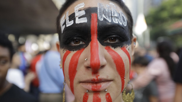 A woman poses for a photo with the words "Not him" written in Portuguese on her face during a protest against Jair Bolsonaro, a far-right presidential candidate in Sao Paulo.