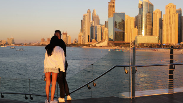 Tourists look at the skyline at sunset, in Dubai. With peak tourism season in full swing, coronavirus infections are surging to unprecedented heights, with daily case counts nearly tripling in the past month.