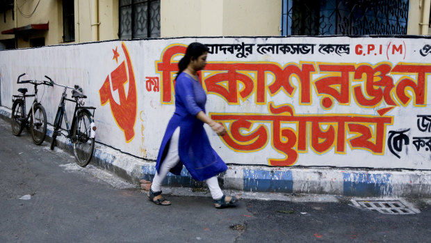 A woman walks past graffiti in Kolkata for the Communist Party of India-Marxist. India's general elections will be held in seven phases from April 11 to May 19. 