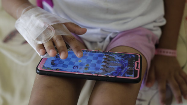 A young dengue patient plays with a smartphone at the San Lazaro government hospital in Manila.