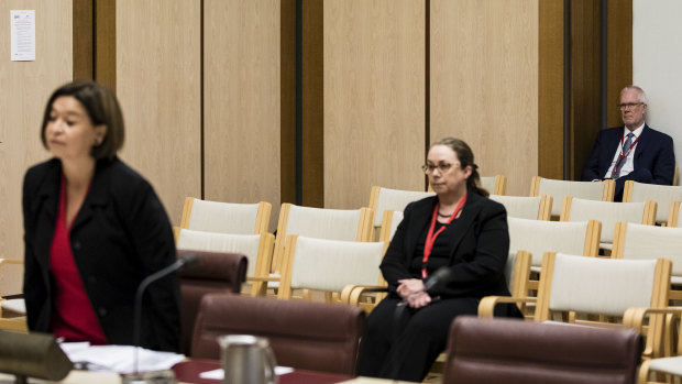 Justin Milne watches on from the  back of the room as Michelle Guthrie gives evidence to the Senate inquiry.