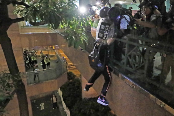 A protester hangs from a bridge as police officers try to pull him up after a scuffle with police.