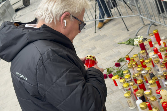 A man lights a candle in Villach, Austria, at the site of the stabbing that left a 14-year-old dead and five other people injured.