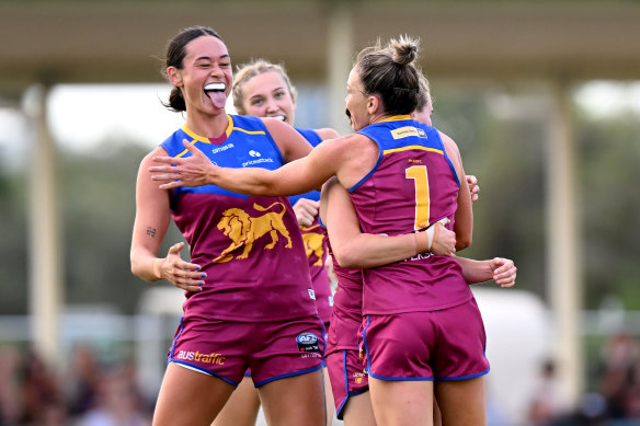 Emily Bates celebrates a goal with Brisbane teammates. 
