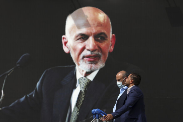 Passengers pass a mural of Afghan president Ashraf Ghani at Hamid Kazrai Airport in Kabul. Ghani fled the capital as the Taliban moved in.