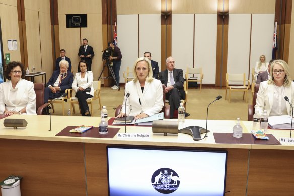 Christine Holgate, centre, wearing suffragette white to a Senate hearing. 