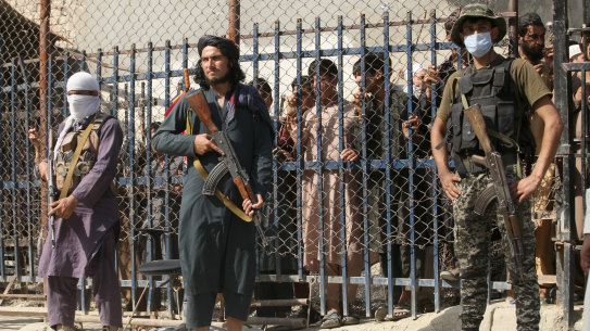 A Pakistani paramilitary soldier, right, and Taliban fighters stand guard on their respective sides  at a border crossing point between Pakistan and Afghanistan, in Torkham.
