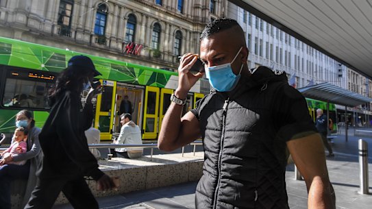 A man walks through Bourke Street Mall in Melbourne with a mask on.