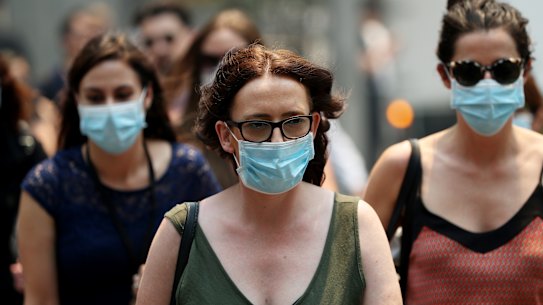 People are seen wearing face masks to protect from smoke haze as they cross a busy city street on December 05, 2019 in Sydney, Australia. Smoke haze continues to hang over the city as more than 50 bushfires continue to burn across New South Wales.
