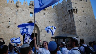 Israelis wave national flags outside the Old City's Damascus Gate in Jerusalem on Sunday.