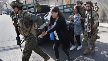 Lebanese army special forces soldiers assist teachers as they flee their school after deadly clashes erupted nearby along a former civil war front-line between Muslim and Christian areas in Beirut.