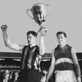 Hawthorn skipper Graham Arthur holds aloft the 1961 premiership cup.