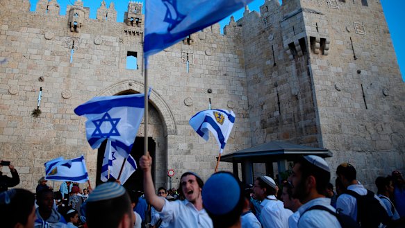 Israelis wave national flags outside the Old City's Damascus Gate in Jerusalem on Sunday.
