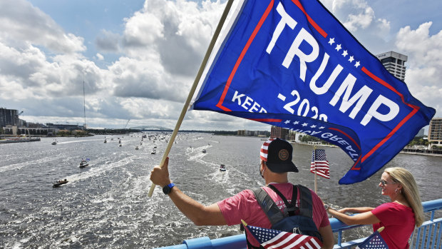 Brian Masotti, left, and Tracey Warren wave flags at the hundreds of boats idling on the St. Johns River during a rally in Jacksonville, Fla., celebrating President Donald Trump's birthday.  
