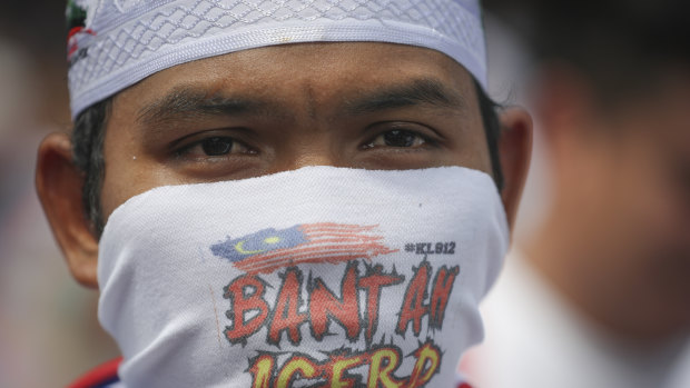 A protester covering his face takes a part in a rally to celebrate the government's move to withdraw plans to ratify a UN anti-discrimination convention  in Kuala Lumpur on Saturday.