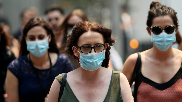 People are seen wearing face masks to protect from smoke haze as they cross a busy city street on December 5, 2019 in Sydney.