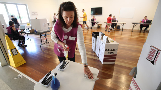 Voting during COVID-19: An election official sanitises a polling booth during the Brisbane council election in March.