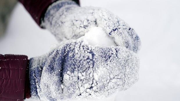 Cristina Lucero’s hands are covered in snow while building a snowman in Houston. 