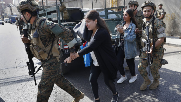 Lebanese army special forces soldiers assist teachers as they flee their school after deadly clashes erupted nearby along a former civil war front-line between Muslim and Christian areas in Beirut.