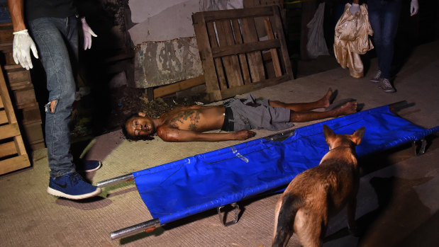 A stray dog walks through the Philippine police crime scene where the body of Rolito Nunez lays on a footpath in Barangay Old Balara, Quezon City. 