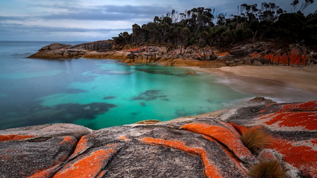 Red rocks border Trousers Point and its beach.