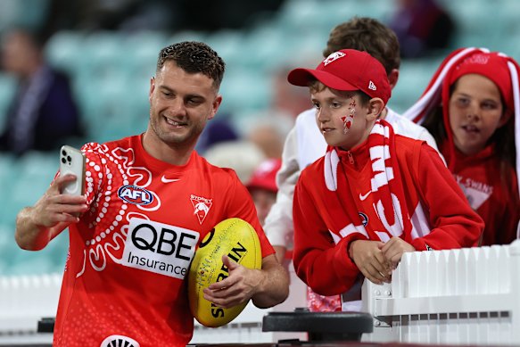 Tom Papley of the Swans poses for a photo with fans pregame.